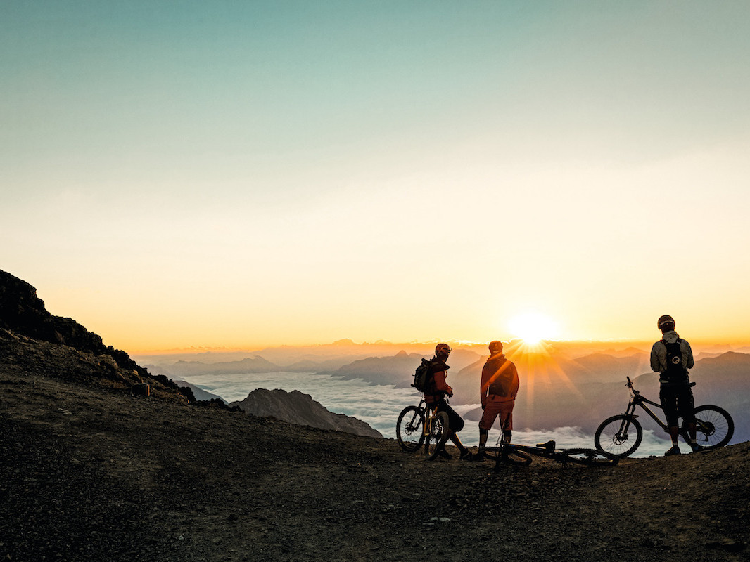 FP Events | Switzerland Tourism/Filip Zuan, Les vététistes profitent du lever du soleil sur le Piz Nair.